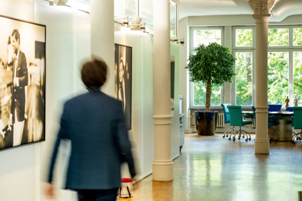 Großzügiges Büro mit runden Säulen, Konferenztisch aus Marmor und großformatigen Bildern von J.F. Kennedy und Romy Schneider an den Wänden.