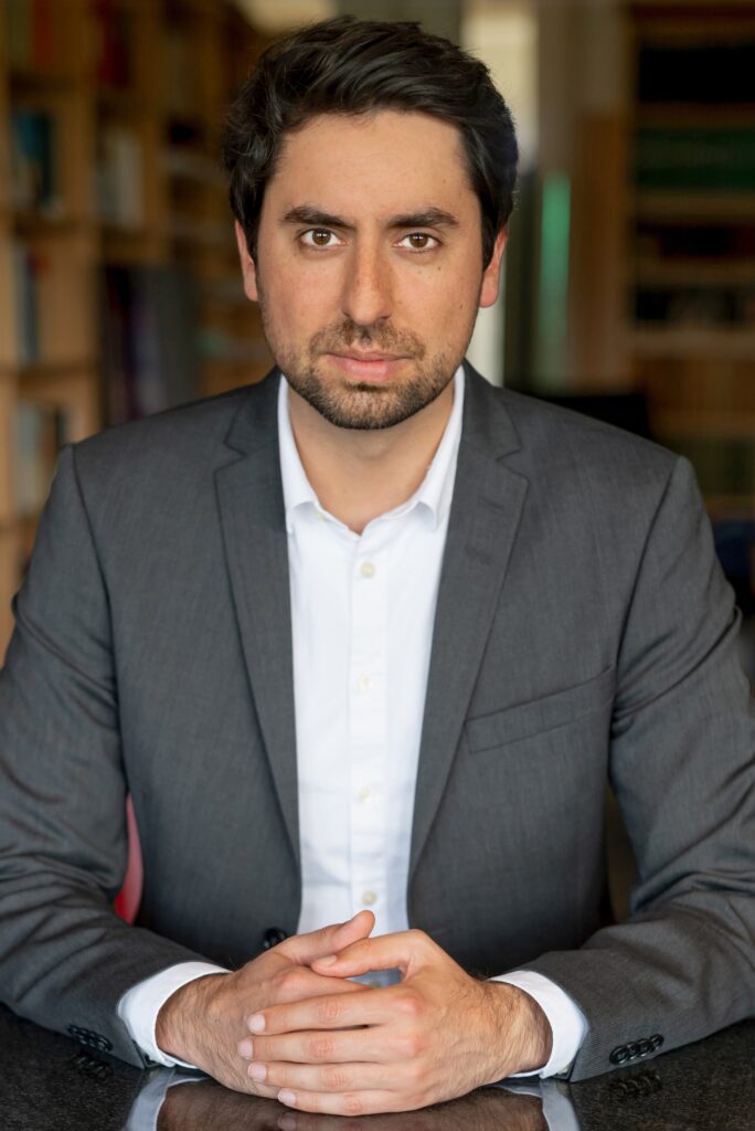 Rechtsanwalt Dilowan Döhring in Anzug sitzend an einem Schwarzen Marmortisch in der Kanzlei.