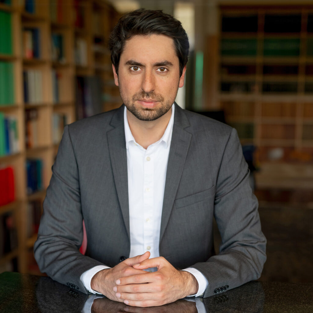 Rechtsanwalt Dilowan Döhring in einem grauen Anzug sitzend an einem schwarzen Mamortisch.